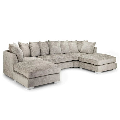 A large corner sofa with a footstool, upholstered in grey fabric with multiple foam-filled cushions, set against a white background.
